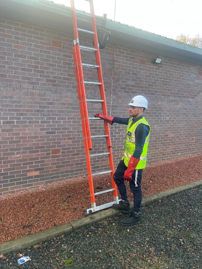 Roofer securing access equipment at a roof
