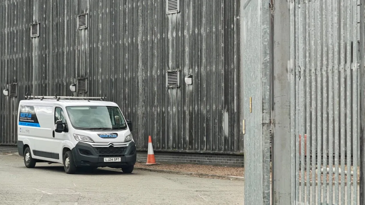 Roof Plan van parked in front of a grey and blue industrial building