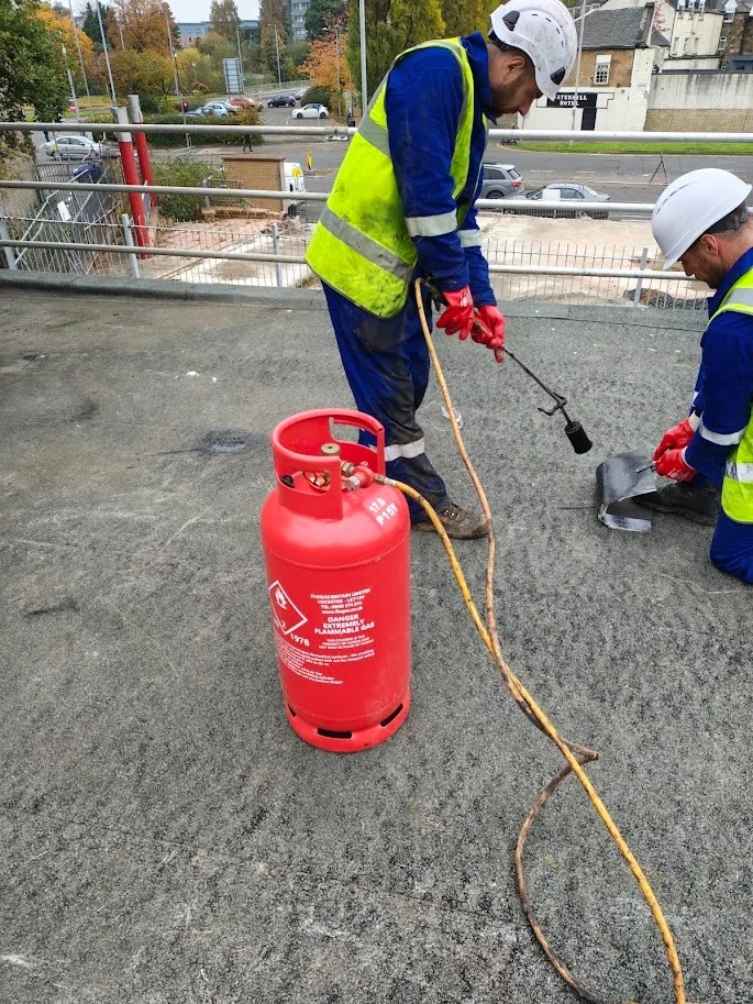 Two roofers using a gas torch on a flat roof